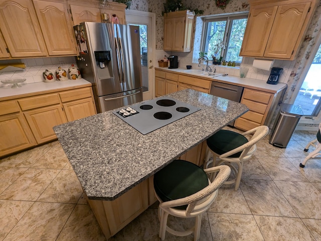 kitchen featuring a kitchen island, light brown cabinets, a breakfast bar area, sink, and appliances with stainless steel finishes