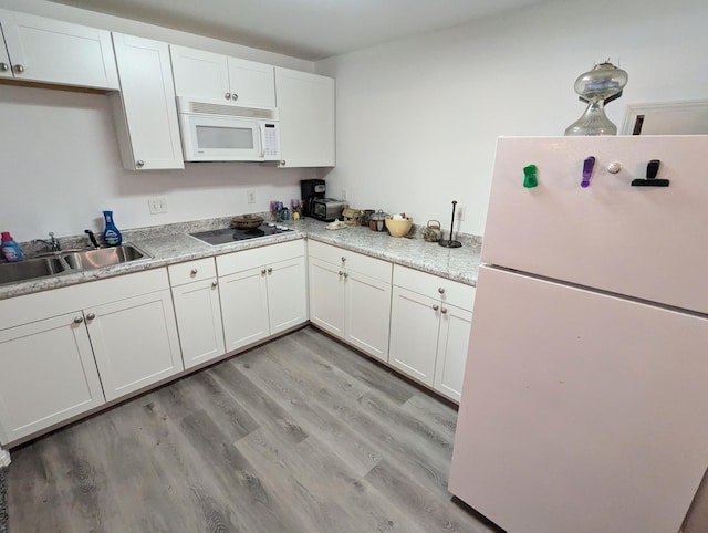 kitchen with white appliances, light hardwood / wood-style floors, white cabinetry, and sink