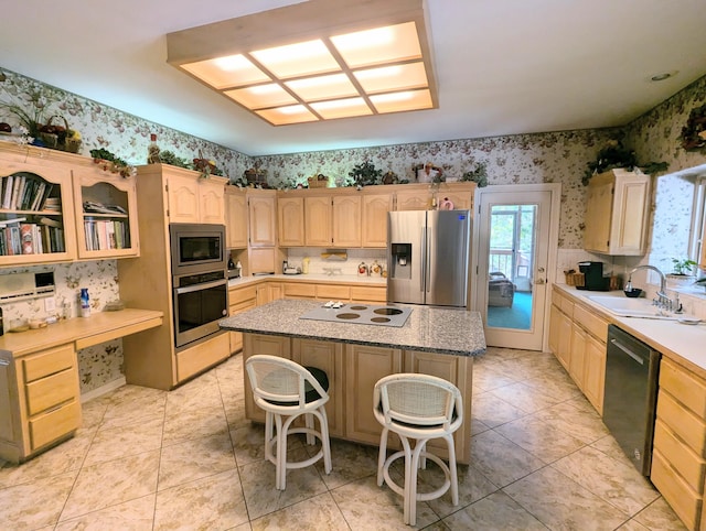 kitchen featuring a kitchen island, light brown cabinets, a kitchen breakfast bar, stainless steel appliances, and sink