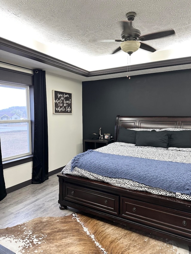 bedroom with light hardwood / wood-style flooring, a textured ceiling, and ceiling fan