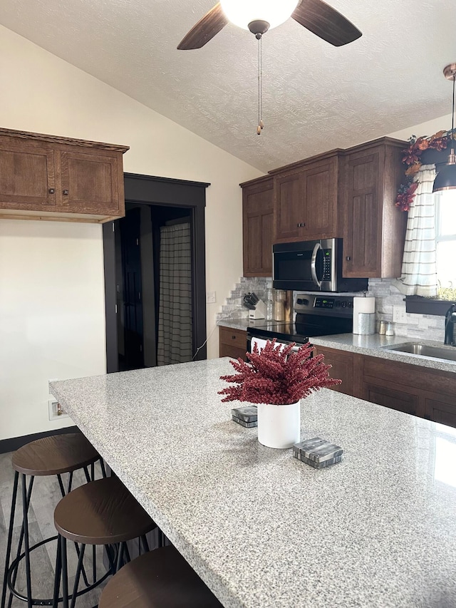 kitchen featuring sink, vaulted ceiling, stainless steel appliances, and backsplash