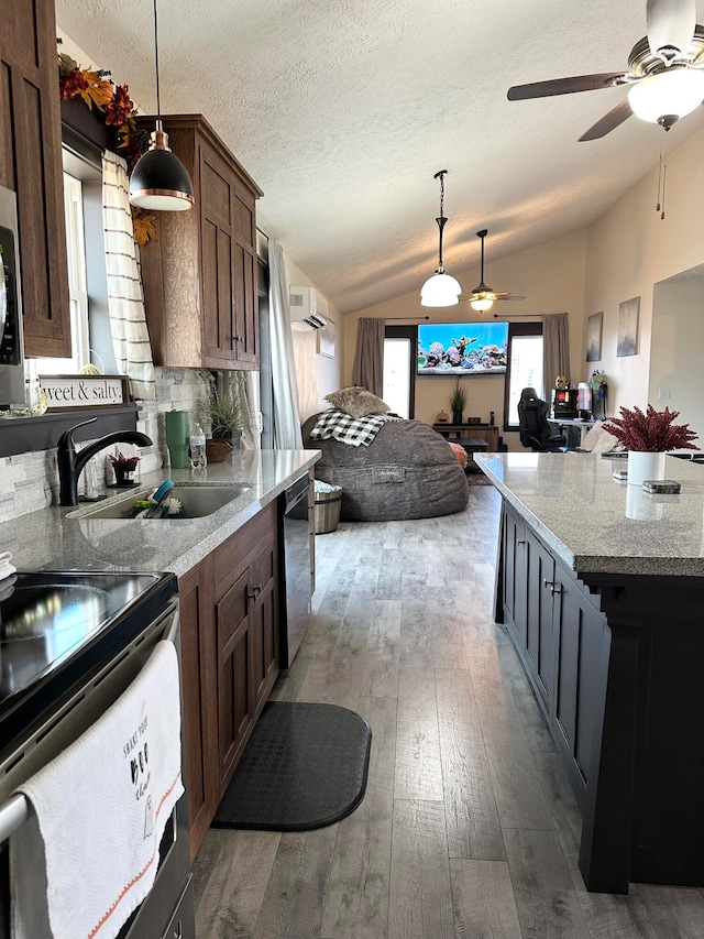 kitchen with sink, light hardwood / wood-style floors, stainless steel appliances, lofted ceiling, and decorative light fixtures