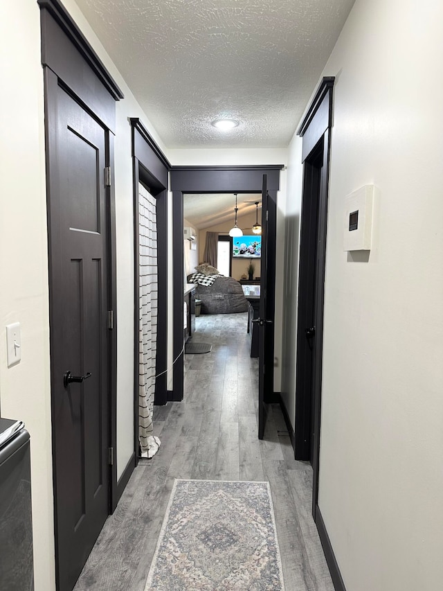 hallway with a textured ceiling and hardwood / wood-style flooring