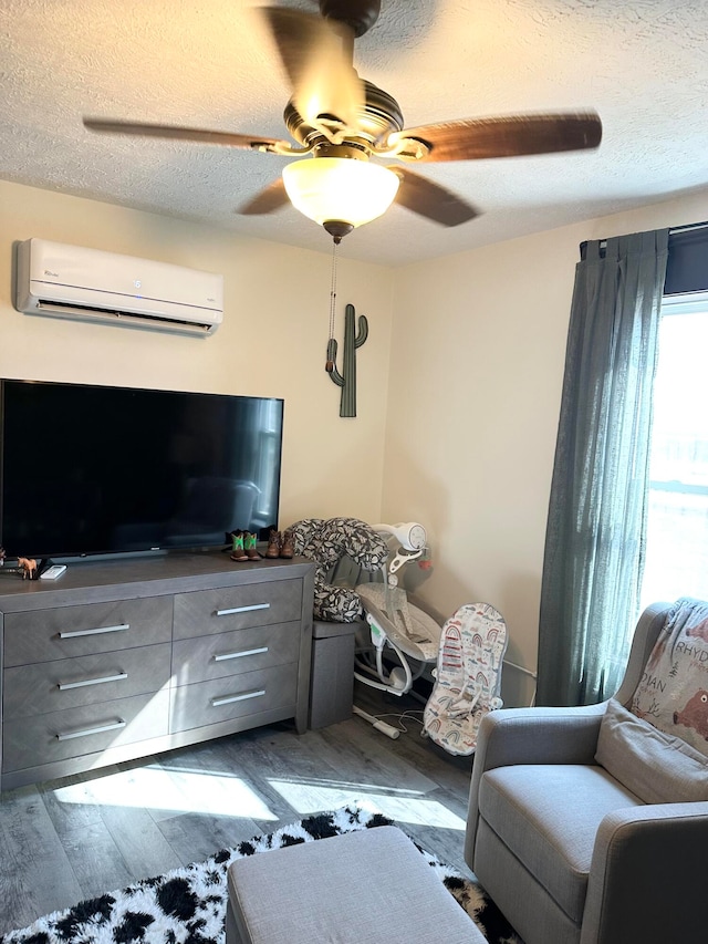 living room featuring ceiling fan, wood-type flooring, a textured ceiling, and a wall unit AC