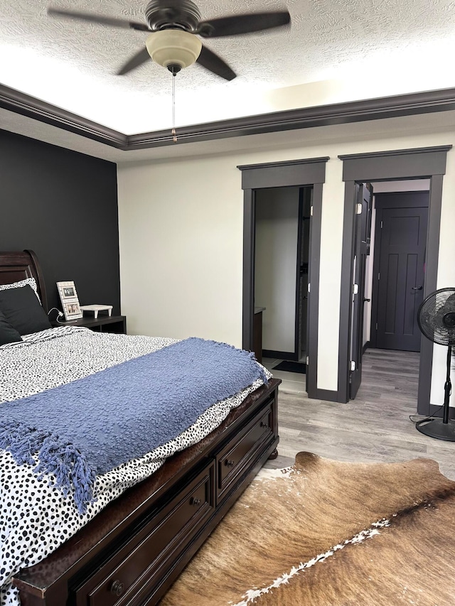 bedroom with ceiling fan, a textured ceiling, and light hardwood / wood-style flooring