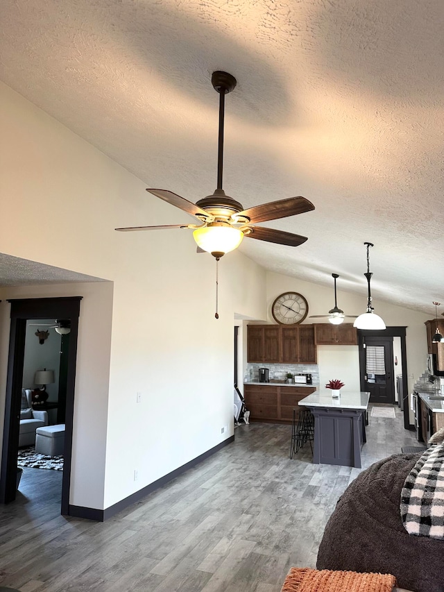 living room featuring ceiling fan, a textured ceiling, vaulted ceiling, and dark hardwood / wood-style flooring