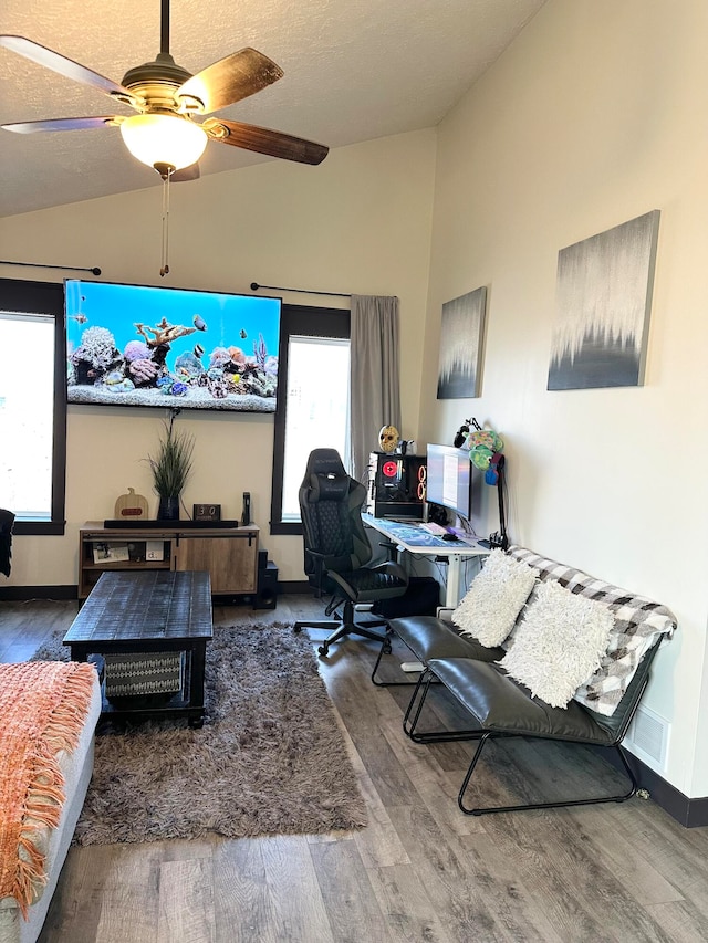 living room with a healthy amount of sunlight, hardwood / wood-style flooring, ceiling fan, and vaulted ceiling