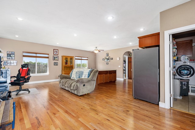 living room with washer / dryer, light hardwood / wood-style flooring, and ceiling fan