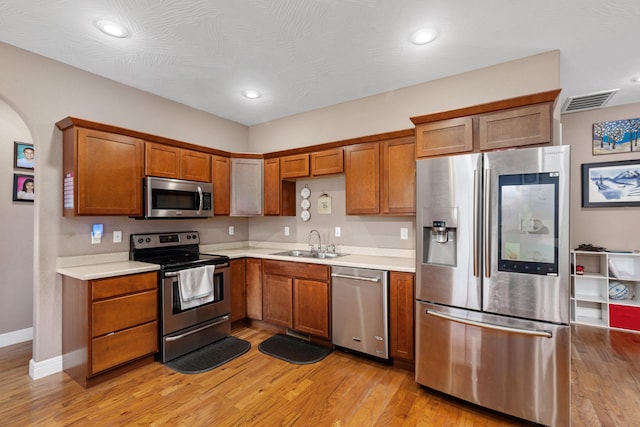 kitchen with sink, light hardwood / wood-style flooring, stainless steel appliances, and a textured ceiling