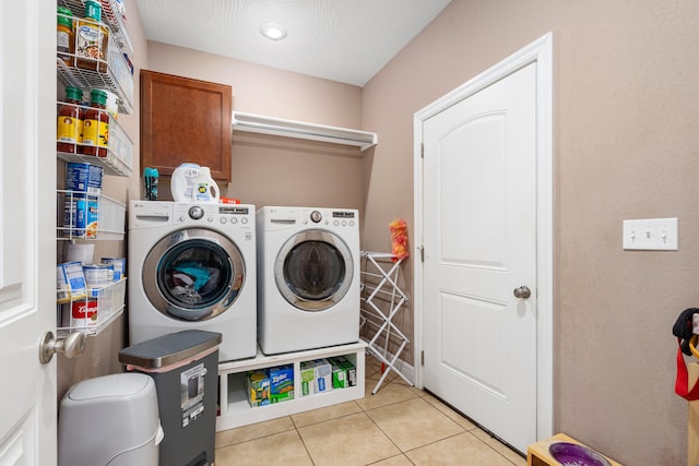 laundry area featuring light tile patterned flooring, washing machine and dryer, and cabinets