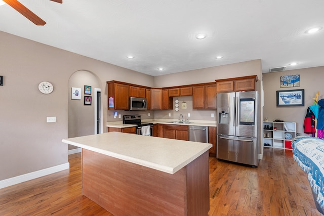 kitchen featuring appliances with stainless steel finishes, sink, wood-type flooring, and a kitchen island