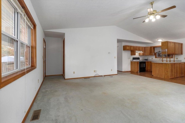 unfurnished living room with lofted ceiling, a textured ceiling, light colored carpet, and ceiling fan