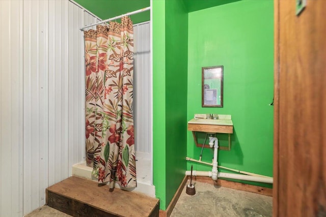 bathroom featuring wood walls, sink, curtained shower, and concrete flooring