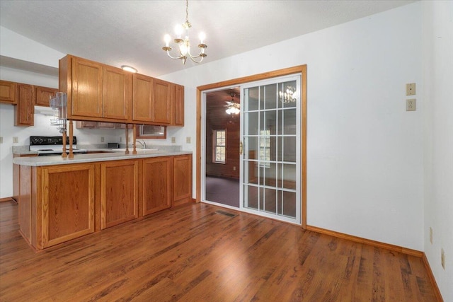 kitchen with white range, hanging light fixtures, wood-type flooring, sink, and ceiling fan with notable chandelier