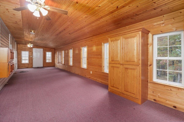 carpeted empty room featuring lofted ceiling, wood ceiling, ceiling fan, and wood walls