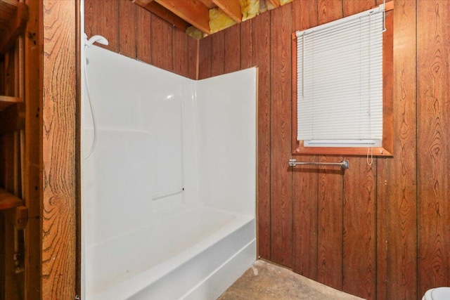 bathroom with wooden walls and shower / tub combination