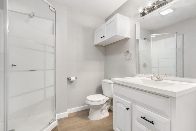 bathroom featuring hardwood / wood-style floors, a shower with door, a textured ceiling, toilet, and vanity