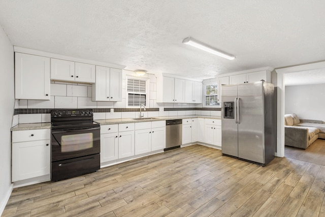 kitchen with white cabinetry, light hardwood / wood-style floors, appliances with stainless steel finishes, and sink