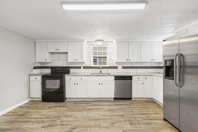 kitchen with backsplash, sink, light wood-type flooring, white cabinetry, and appliances with stainless steel finishes