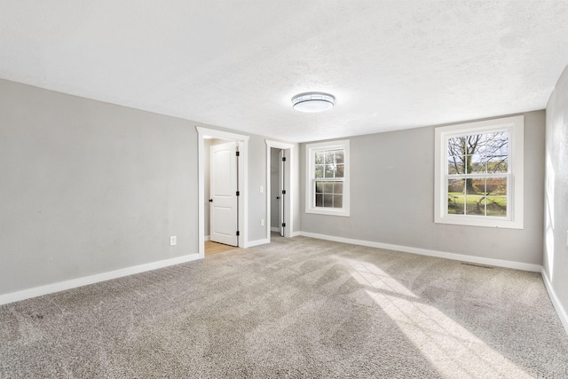 empty room with light carpet and a textured ceiling