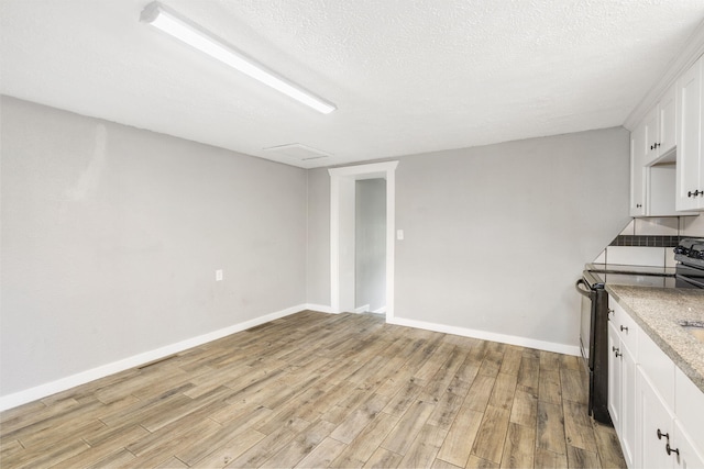 kitchen featuring light hardwood / wood-style floors, white cabinetry, and black electric range