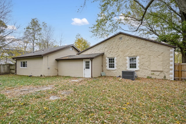 rear view of house featuring central AC and a lawn