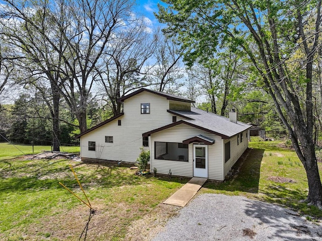 rear view of house featuring a lawn and a chimney