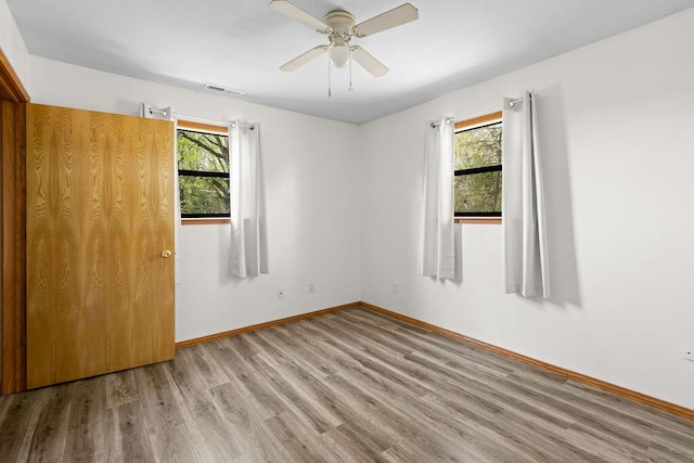 unfurnished bedroom with baseboards, ceiling fan, wood finished floors, and visible vents