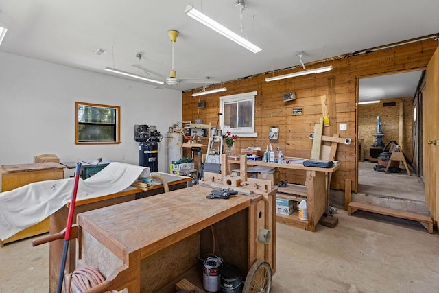 miscellaneous room with unfinished concrete floors, a workshop area, wooden walls, and visible vents