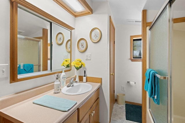 full bathroom with a shower with door, visible vents, tile patterned floors, and vanity