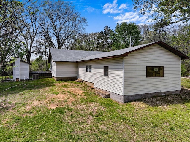 view of side of home with central AC, a yard, and crawl space
