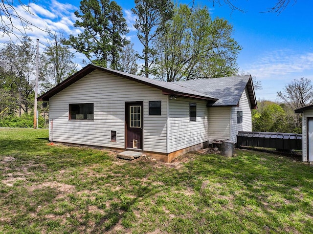 back of house with a shingled roof and a yard