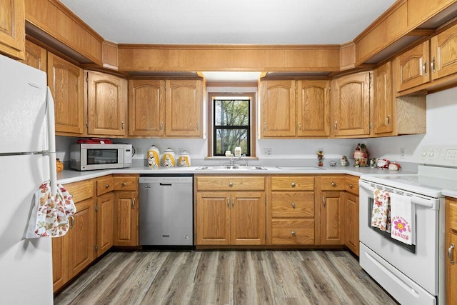 kitchen with white appliances, light wood-style floors, light countertops, brown cabinets, and a sink