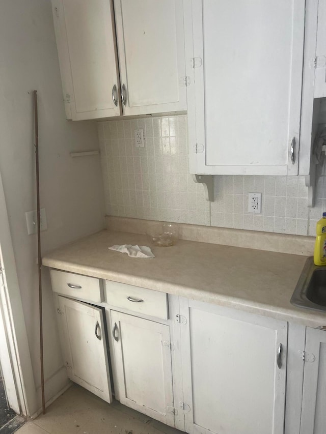 kitchen featuring tasteful backsplash, sink, and white cabinets