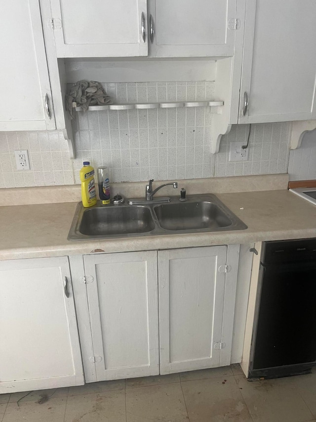 kitchen featuring black dishwasher, decorative backsplash, sink, and white cabinets