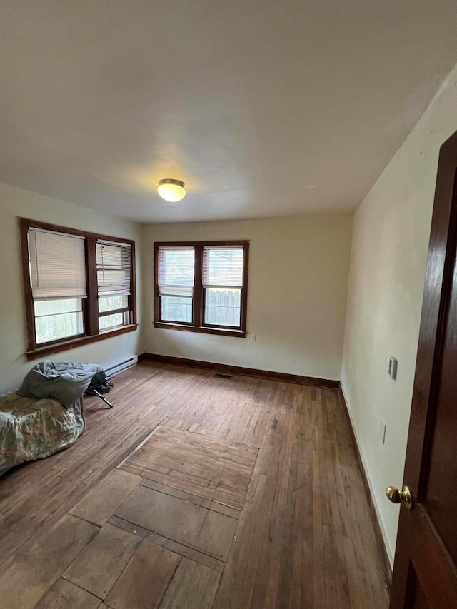 unfurnished room with a baseboard heating unit and hardwood / wood-style flooring