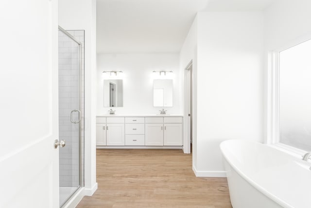 bathroom featuring vanity, hardwood / wood-style flooring, and plus walk in shower