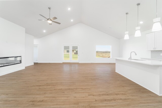 unfurnished living room featuring sink, high vaulted ceiling, light hardwood / wood-style floors, and ceiling fan