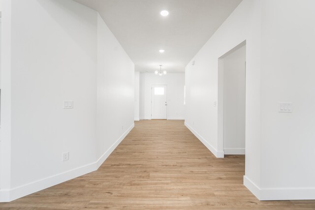 hall with a notable chandelier and light hardwood / wood-style floors