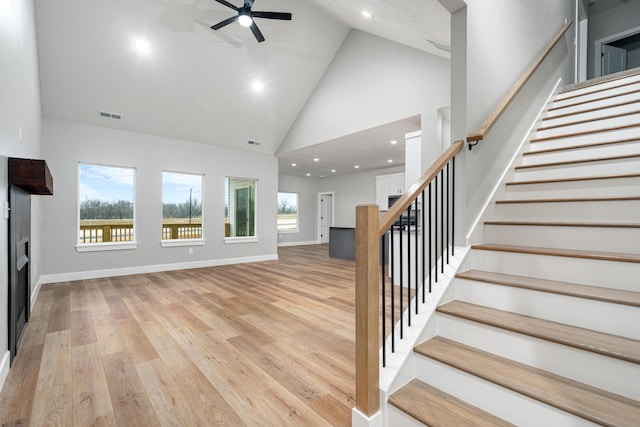 unfurnished living room with high vaulted ceiling, ceiling fan, and light wood-type flooring