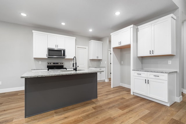 kitchen featuring stainless steel appliances, sink, a center island with sink, and white cabinets