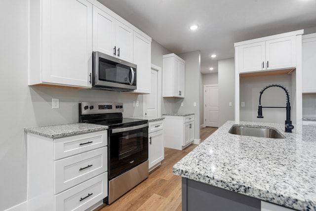 kitchen with light stone countertops, appliances with stainless steel finishes, sink, and white cabinets