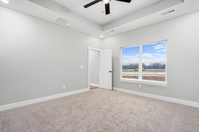 spare room featuring ceiling fan, a raised ceiling, and carpet