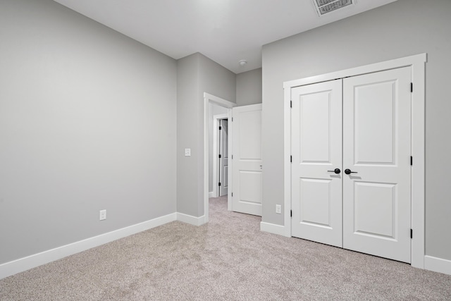 unfurnished bedroom with light carpet and a closet