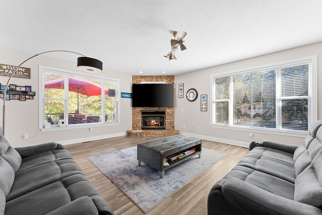 living room with light hardwood / wood-style flooring, a textured ceiling, a wealth of natural light, and a fireplace