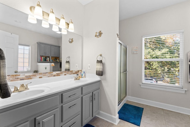 bathroom with vanity, a healthy amount of sunlight, a shower with shower door, and tile patterned flooring