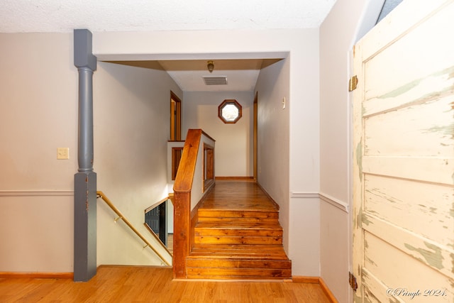 stairway with hardwood / wood-style floors and a textured ceiling