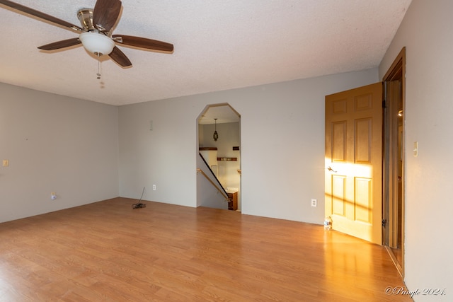 empty room with a textured ceiling, light wood-type flooring, and ceiling fan