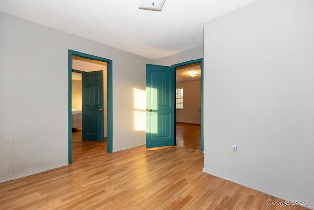 unfurnished bedroom with light hardwood / wood-style floors and a textured ceiling