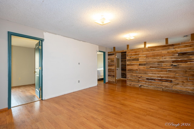 empty room with a textured ceiling and light hardwood / wood-style flooring